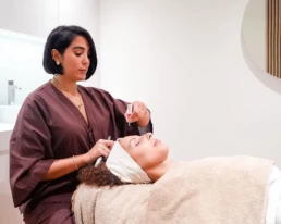 Praticienne r&eacute;alisant un soin signature du visage sur une cliente allong&eacute;e, en cabine chez About Your Skin &agrave; Bruxelles