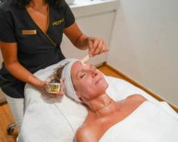 Praticienne appliquant un soin actif &agrave; la main sur le front d'une cliente allong&eacute;e, chez About Your Skin &agrave; Bruxelles