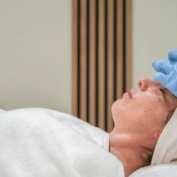 Préparation d'un soin du visage, cliente allongée, chez About Your Skin à Bruxelles