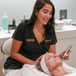 Praticienne r&eacute;alisant un soin du contour de l'&oelig;il &agrave; l'appareil fin sur une cliente allong&eacute;e, chez About Your Skin &agrave; Bruxelles